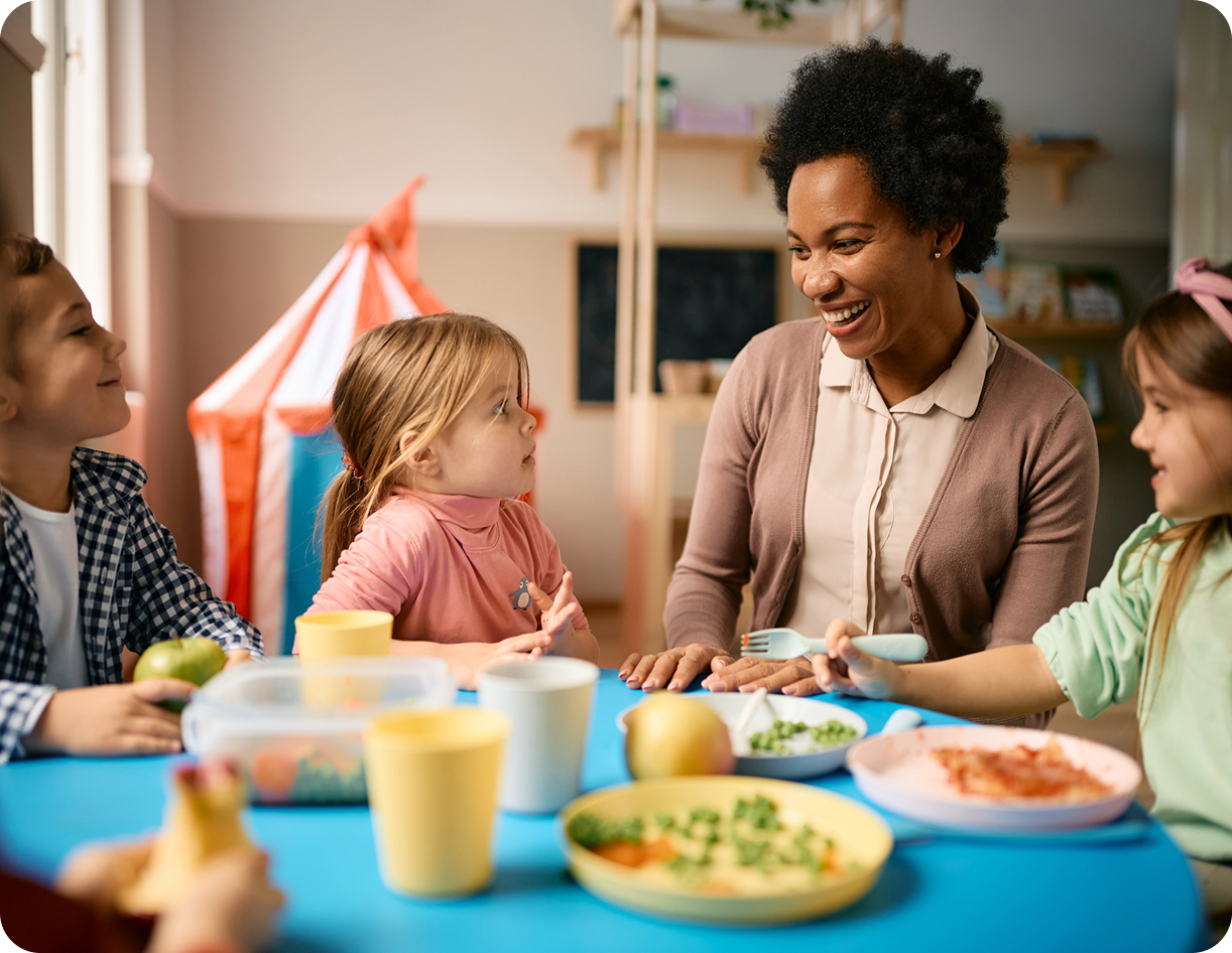 Teacher and children enjoying meal together.