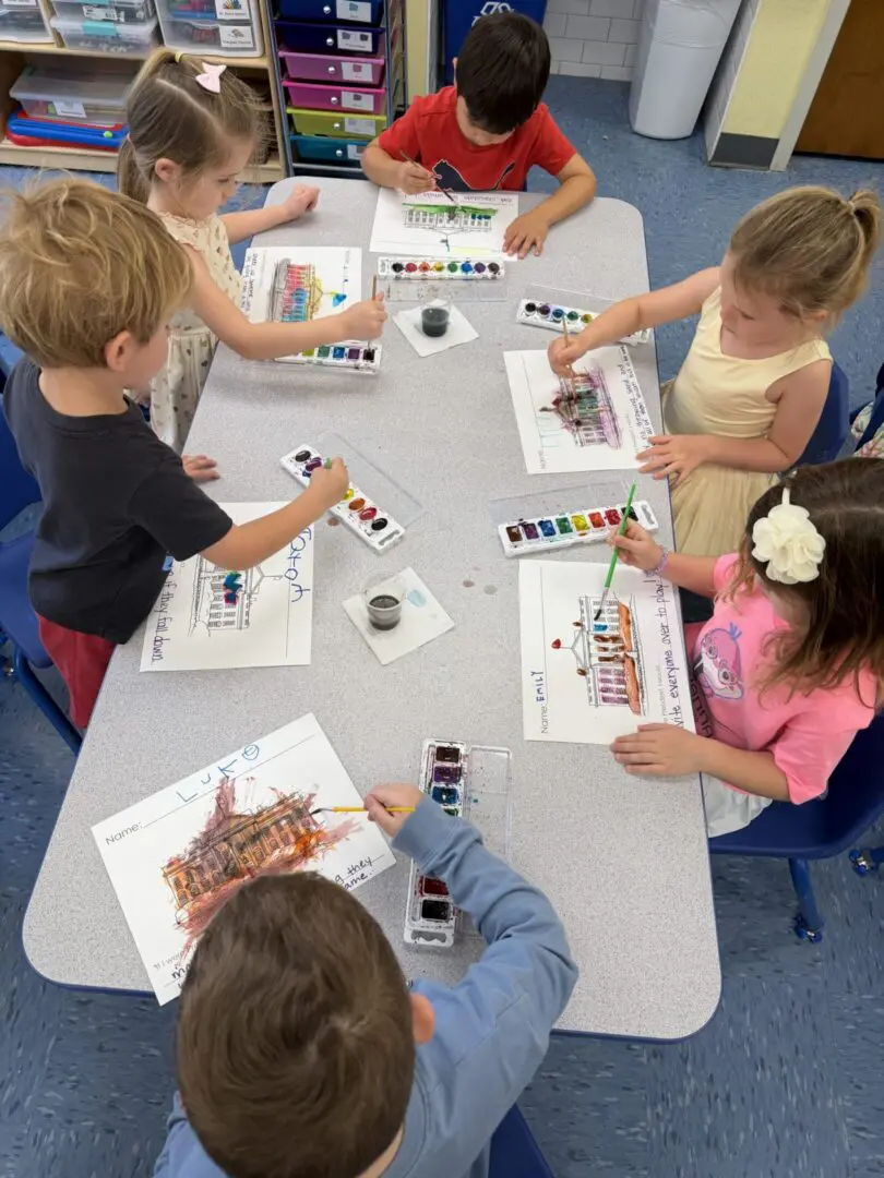Children painting with watercolors at table